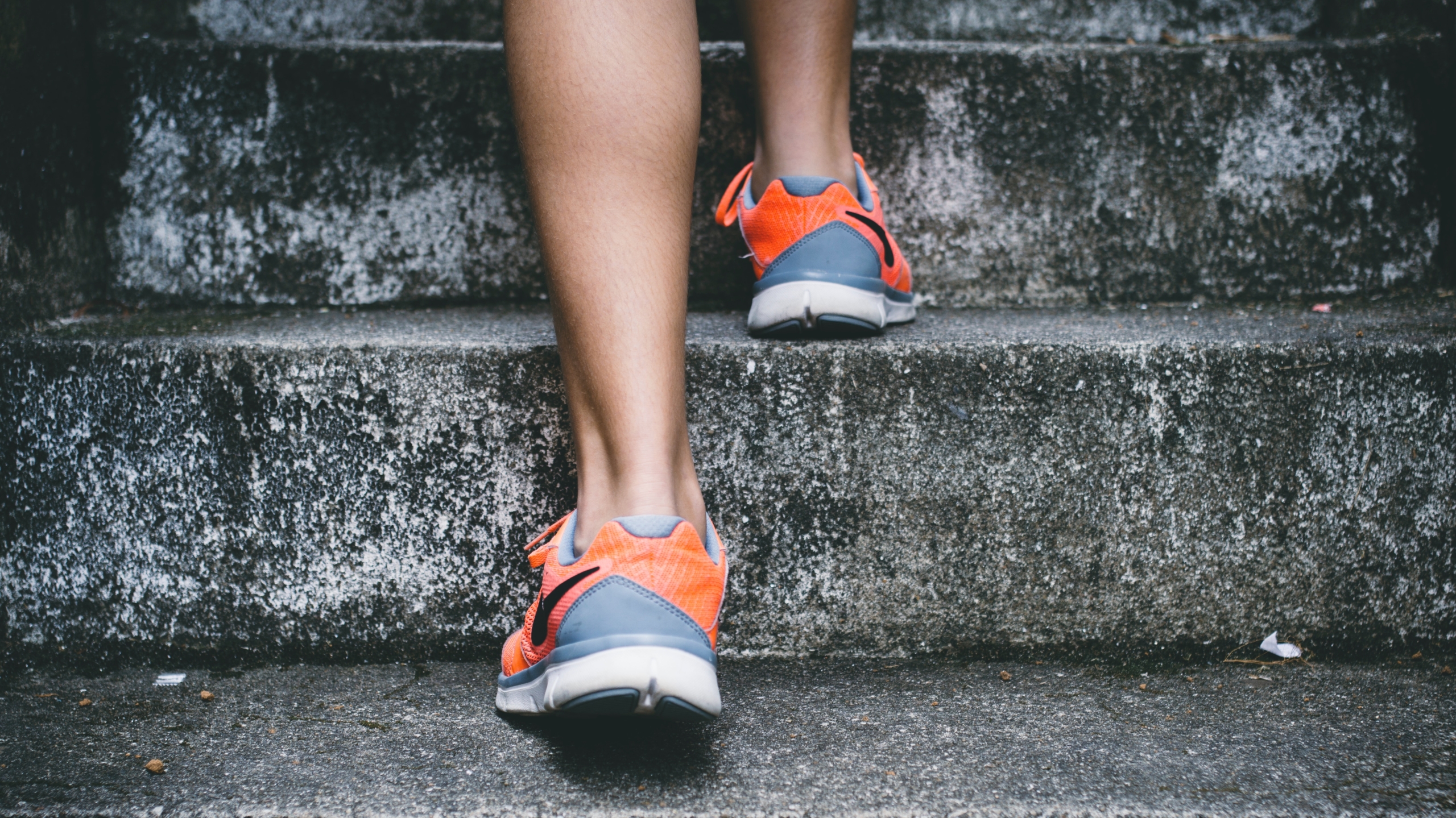 Person walking up concrete steps in orange and blue trainers